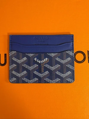 Korthållare - Snyggt blått kortfodral  med det klassiska vita och gråa mönstret. Fodralet har flera kortfack och är tillverkat i slitstarkt canvasmaterial med läderdetaljer. Perfekt för dig som vill ha en stilren och exklusiv accessoar.