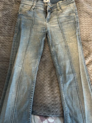 Ljusblå bootcut jeans Bershka - Säljer ett par ljusblå bootcut jeans med markerade pressveck framtill. Jeansen har klassisk femficksdesign, dubbla knappar i midjan och är tillverkade i denim med lätt tvättad look. Perfekta för en avslappnad men trendig stil.