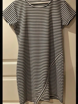 Randig kortklänning från Jacqueline de Yong  - Säljer en randig kortklänning från Jacqueline de Yong. Klänningen har korta ärmar och en rak passform med ett diagonalt band som detalj framtill. Perfekt för dig som gillar enkel men snygg stil. Jag har normal strl M och denna passar mig även om de står XL, den är väldigt stretchig, kan skicka mått om de önskas!