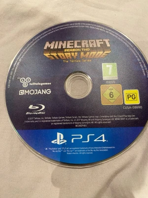 Minecraft Story Mode Season Two PS4 - Minecraft Story Mode Season Two till PS4, ett äventyrsspel från Telltale Games. Skivan är rund och har blå och gul design med spelets logga tryckt på ovansidan. Materialet är klassisk Blu-ray-skiva och spelet är märkt för åldersgrupp 7+.funkar inte