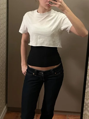 Vit croppad t-shirt - Säljer en enkel och stilren vit croppad t-shirt med rund hals och korta ärmar. Perfekt att matcha med höga jeans eller kjol för en avslappnad look. Eller över ett linne. Materialet känns mjukt och skönt mot huden.