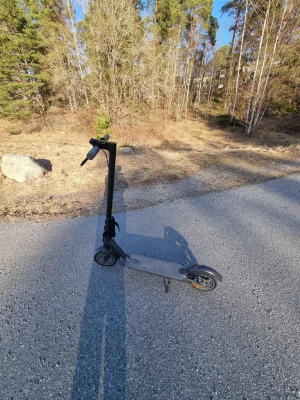 Svart elscooter med digital display - Säljer en svart elscooter med stilren design och digital display på styret. Scootern har handbroms, ringklocka och gula reflexdetaljer. Perfekt för smidig transport i stan eller till skolan. Laddas enkelt via eluttag.