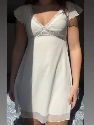 Vit kort klänning  - En jättefin vit somrig klänning, perfekt till studenten, avslutningar eller bara nu till sommaren. Den har fina spetsdetaljer och en v-ringning både fram och bak. Det finns en dragkedja på sidan och ett snöre i tyggen man kan knyta. Jag köpte den på en marknad i Spanien men har aldrig fått användning av den tyvärr.🥰