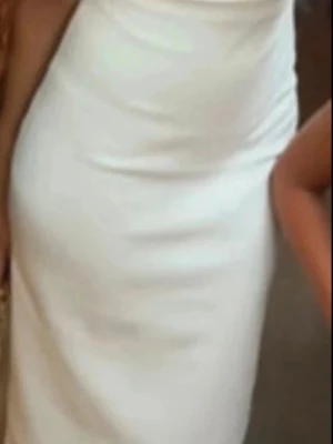 Vit långklänning med smal passform - Elegant vit långklänning med smal passform och enkel, stilren design. Klänningen är ärmlös och har en klassisk siluett som framhäver figuren. Perfekt för dig som gillar minimalistisk och tidlös stil.