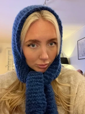 Blå stickad balaclava med knytband - Mysig blå handstickad balaclava med breda knytband under hakan. Perfekt för kalla dagar och enkel att styla till olika outfits. Materialet är alpacka, ull och mohair 💙