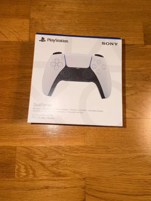 Sony PlayStation 5 DualSense handkontroll - Trådlös DualSense handkontroll till PlayStation 5 från Sony. Kontrollen är vit med svarta detaljer och har en futuristisk design. Passar även till PC, Mac och mobil. Ergonomisk form och avancerade funktioner som haptisk feedback och adaptiva triggers.