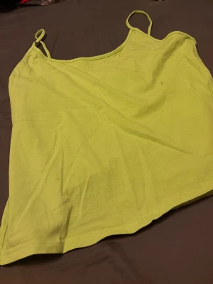 Ljusgul linnetopp med smala band - Snygg ljusgul linnetopp med tunna axelband och enkel design. Perfekt för varma dagar och enkel att matcha med olika stilar. Mjuk och lätt i materialet för en bekväm känsla.