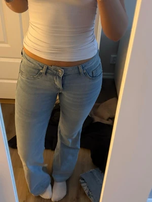 Ljusblå raka jeans med låg midja - Säljer ett par ljusblå jeans med rak passform och låg midja. Klassisk femficksmodell och stängs med dragkedja och knapp. Perfekta till en avslappnad stil och passar till det mesta. Materialet är mjukt denim i bomull.