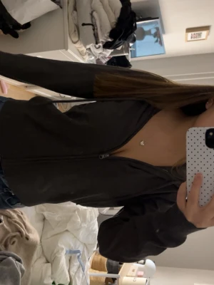 Mörkgrå zip-hoodie med huva - Mörkgrå hoodie med dragkedja och huva. Tröjan har långa ärmar och en enkel, stilren design utan synliga loggor eller mönster. Perfekt för en avslappnad look och enkel att matcha med jeans eller leggings.