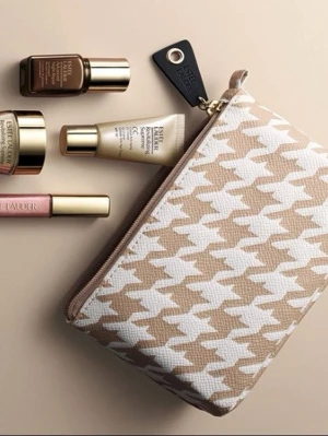 Beige och vit necessär Estée Lauder - Snygg necessär från Estée Lauder i beige och vitt med klassiskt hundtandsmönster. Praktisk dragkedja med svart och guld detalj. Perfekt för smink eller småprylar. Tillverkad i tåligt tygmaterial.