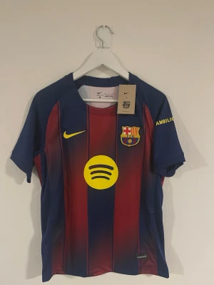 Barcelona 2025/26 hemma tröja (#10 Lamine Yamal) - Säljer en riktigt snygg Barcelona-tröja (nummer 10). Blå och röd med gula detaljer, i riktigt fint skick – aldrig använd. Perfekt för samlare eller för dig som gillar klassiska fotbollströjor. Storlek passar som S. Tröjan kommer i original förpackning. Om du har några frågor eller vill se fler bilder är de bara att skriva!🙂 Kolla gärna på mina andra artiklar, så kanske du hittar något du gillar!