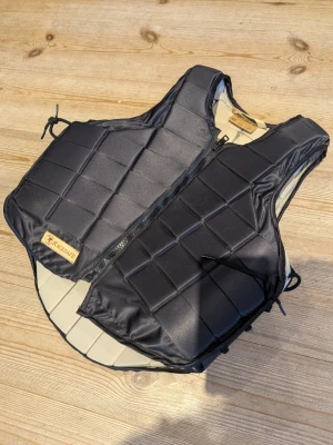 Racesafe ridväst - Racesafe säkerhetsväst i bra skick. Använd ett fåtal gånger. Fin och stilren. Knytning i sidorna för att anpassa storlek och passform. 
