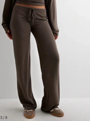 Bruna vida mjukisbyxor med dragsko - Mysiga bruna mjukisbyxor med breda, raka ben och dragsko i midjan. Tillverkade i ett mjukt och stretchigt material som ger en avslappnad och skön känsla. Perfekta för chill dagar hemma eller när du vill ha en casual look. Har en liten skada, fast den är fixad så de syns inte.