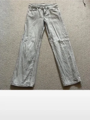 Gråa vida jeans med raka ben - Säljer ett par gråa jeans med raka, vida ben och klassisk femficksdesign. Jeansen har normal midja och är tillverkade i denim. Perfekta för en avslappnad och trendig stil.