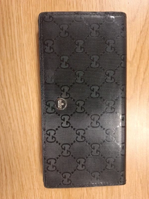 Vintage Gucci plånbok - Snygg svart plånbok från Gucci med klassiskt GG-monogram i hela designen. Tillverkad i tåligt material med en elegant och stilren look. Läder på insidan. Perfekt för dig som gillar exklusiva accessoarer och vill ha något som sticker ut.