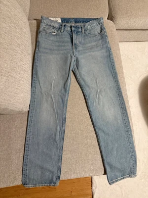 Ljusblå raka jeans - Säljer ett par ljusblå jeans med rak passform och klassisk femficksdesign. Jeansen har normal midja och är tillverkade i denim med en snygg tvättad look. Perfekta för en avslappnad stil och passar till det mesta.