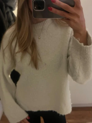 Vit stickad tröja  - En vit stickad tröja som blivit missfärgad, har ett hål under armhålan samt en fläck på framsidan. Det går säkert att få bort fläcken samt sy ihop hålet🩷