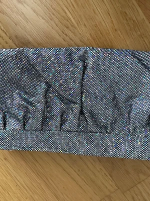 Glittrig silver kuvertväska - Säljer en glittrig kuvertväska i silver med små skimrande stenar över hela ytan. Väskan har en rektangulär form och stängs med dragkedja. Insidan är fodrad i vitt tyg och har ett huvudfack. Perfekt för att addera lite extra bling till din outfit!