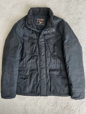 Woolrich Field Jacka - Snygg och eftertraktad field jacka från Woolrich! Fint skick inga defekter. Storlek L, passar dig som är 185cm+. Kontakta mig för fler frågor och funderingar!