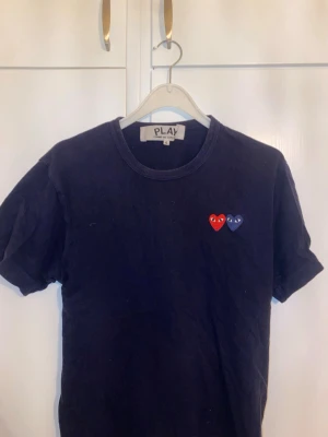 Cdg  t-shirt - Marinblå t-shirt från Comme des Garçons PLAY med två små hjärtan, ett rött och ett blått, broderade på bröstet. Använt men bra skick, inga defekter, förutom lite lite färgblekt. 
