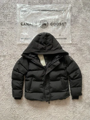 Canada Goose - Macmillan Parka - Canada Goose MacMillan Parka – Black Label – strl M  Säljer en Canada Goose MacMillan Parka Black Label i nyskick. Endast använd ett fåtal gånger, inga fläckar, hål eller slitage.  Varm, stilren och tidlös modell som passar perfekt under vintern. Förvarad i rök- och djurfritt hem.  Storlek: M Färg: Svart Black Label-modell