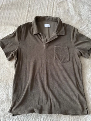 Beige polotopp från Studio Total - Snygg beige polotopp från Studio Total i mjukt material. Klassisk krage, kort ärm och bröstficka ger en clean look. 