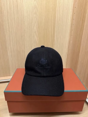 Loro piana keps - Säljer en snygg Loro Piana keps i navy blått (ull). Lätt, bekväm och enkel att bära till allt. Fint skick, perfekt för dig som vill ha en clean keps med bra kvalitet och farg som sticker ut lagom mycket. Obs Box medföljer inte