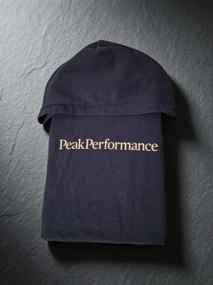 Svart hoodie från Peak Performance - Snygg svart hoodie från Peak Performance med klassisk logga i vitt på bröstet. Hoodien har huva, ribbade muddar och en stor magficka. Tillverkad i mjukt bomullsmaterial som är skönt att bära. Perfekt för en avslappnad och sportig stil.