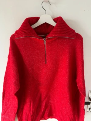 Röd stickad tröja med dragkedja - Snygg röd stickad tröja med hög krage och dragkedja framtill. Aldrig använd då färgen inte passar mig.