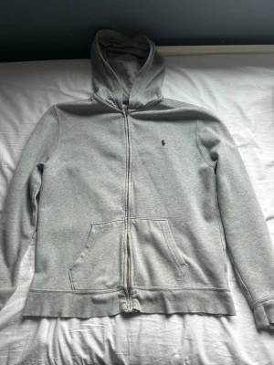 Grå hoodie med dragkedja från Polo Ralph Lauren - Klassisk grå hoodie med dragkedja från Polo Ralph Lauren.Perfekt för en chill och avslappnad stil. Andvänd några gånger, men inga defekter. Nypris 1300. Mitt pris: 400. Passar Xs och S 