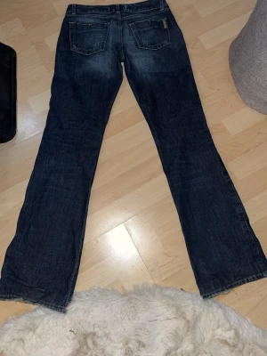 Mörkblå bootcut jeans - Säljer ett par mörkblå bootcut jeans med klassiska bakfickor. Jeansen har en avslappnad passform och är tillverkade i denim. Perfekta för en casual och trendig look.