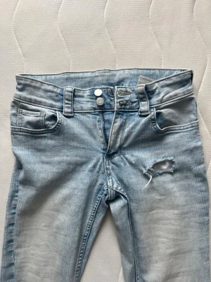 Ljusblå slitna bootcut jeans från hm  - Säljer ett par ljusblå bootcut jeans med hål som jag klippt själv 