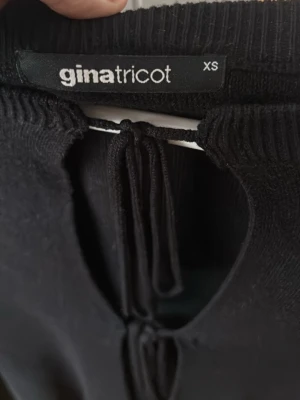Svart stickad tröja Gina Tricot - Snygg svart stickad tröja från Gina Tricot i storlek XS. Tröjan har långa ärmar och trendiga knytningar framtill som ger en cool look. Rund halsringning och mjukt material som känns skönt mot huden. 