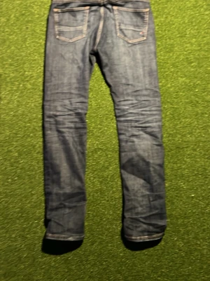 Mörkblå raka jeans med kontrastsömmar - Säljer ett par mörkblå jeans med raka ben och klassiska kontrastsömmar. Jeansen har fem fickor och knappgylf. Perfekta till vardags för en avslappnad men snygg stil. Materialet är denim i bomull. Tommy hilfiger