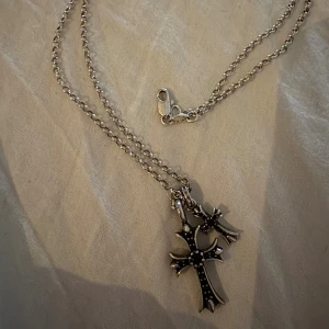 Chrome Hearts Double cross Silverhalsbans - Snyggt silverfärgat halsband med två korsformade hängen i olika storlekar. Kedjan är tunn och har ett klassiskt lås. Hängena har detaljerade kanter och små pärlliknande dekorationer på framsidan. Perfekt accessoar för dig som gillar stilrena smycken med edge.