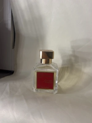 Baccarat Rouge 540 Eau de Parfum - Lyxig parfym från Maison Francis Kurkdjian, Baccarat Rouge 540. Flaskan är fyrkantig i genomskinligt glas med en elegant guldfärgad kork och röd etikett framtill. Doften är känd för sin unika, sensuella och exklusiva karaktär.