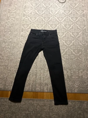 Svarta slim fit jeans LAB Industries - Säljer ett par svarta slim fit jeans från LAB Industries, modell LUKE. Jeansen har klassisk femficksdesign, dragkedjegylf och raka ben. Perfekta för dig som gillar en smalare passform och stilren look.