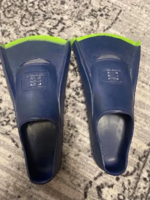Blå och gröna simfenor - Ett par simfenor i blått med gröna detaljer, tillverkade i gummi. Fenorna har stängd häl och är märkta med storlek 40-41. Perfekta för träning och simning i pool eller hav.