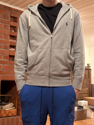 Grå Ralph Lauren zip hoodie - Säljer min gråa Ralph Lauren zip hoodie för den är för liten. Använd ett fåtal gånger men i perfekt skick. Hör av er vid funderingar.