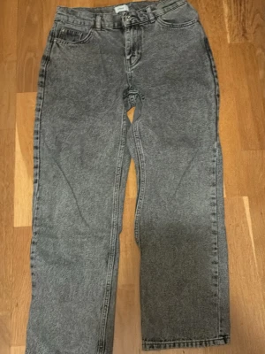 Grå tvättade jeans från Grunt - Säljer ett par grå tvättade jeans från Grunt med rak passform och klassisk femficksdesign. Jeansen har hög midja och är tillverkade i ett robust denimtyg. Perfekta för en avslappnad och trendig look.