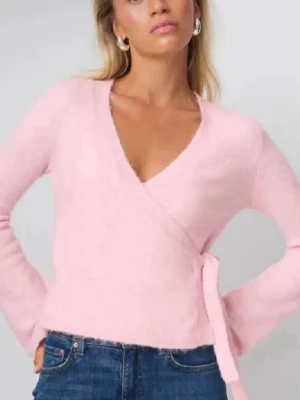 Ljusrosa omlottkofta med knytband - Supersöt ljusrosa omlottkofta med knytband i sidan och v-ringad hals. Koftan har långa ärmar och är gjord i ett mjukt, stickat material som känns fluffigt. Perfekt att slänga över en topp för en chill och trendig look.