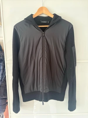 J-Lindeberg cardigan storlek S - Väldigt snygg och stilren svart cardigan från J-Lindeberg. Perfekt nu till våren men även andra årstider då den håller värme väldigt bra.  Nypris 2499:-, Kontakta vid frågor.