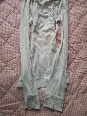 Hoodie 2000s - Långärmad vit hoodie från RETRO med trycket 'RETRO ESTABLISHED 1964' i orange och marinblått på ryggen. Hoodien har dragsko i huvan och är tillverkad i ett tunt, mjukt material som känns skönt mot huden. Perfekt för en avslappnad och stilren look.