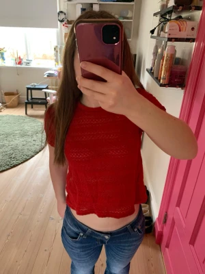 Röd croppad topp - Säljer en röd croppad topp med korta ärmar och fina detaljer. Toppen har en avslappnad passform och är perfekt för dig som vill ha en enkel men ändå snygg look. Passar till både jeans och kjol.