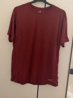 Vinröd kortärmad t-shirt från Peak Performance - En enkel och stilren vinröd t-shirt från Peak Performance. T-shirten har rund halsringning, korta ärmar och diskret logga nere vid fållen. Perfekt för en avslappnad look och tillverkad i mjukt material.