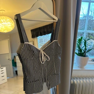 Rutig svartvit korsettopp från Zara - Trendig korsettopp i svartvitt från Zara. Superfin till sommaren. Går inte längre att få tag i. I storlek S men passar mig som brukar ha M på Zara. 