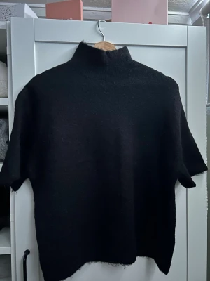 Svart stickad tröja Gina Tricot - Svart stickad tröja från Gina Tricot i ullblandning. Tröjan har korta ärmar och hög hals💞