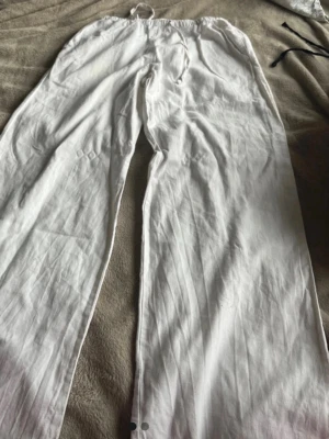 Vita och svarta linnebyxor - Två par linnebyxor i vitt och svart med raka ben och resår i midjan. Perfekta för en avslappnad och stilren look. Luftiga och sköna, tillverkade i linne för maximal komfort under varma dagar.