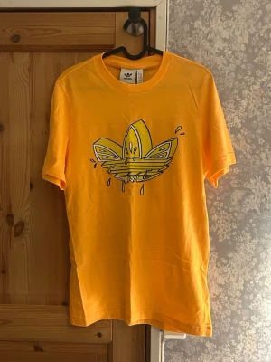 Gul Adidas t-shirt med grafiskt tryck - Gul adidas t-shirt med tryck. Mycket bra skick aldrig använd. Hör av vid frågor!💗