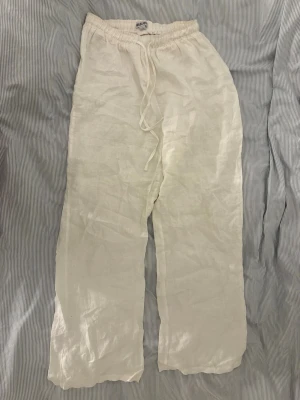 Vita linnebyxor från Madlady - Säljer ett par vita linnebyxor från Madlady i storlek S/Tall. Byxorna har en avslappnad passform, resår i midjan och dragsko för extra komfort. Tillverkade i ett lätt och luftigt linnematerial, perfekta för varma dagar.